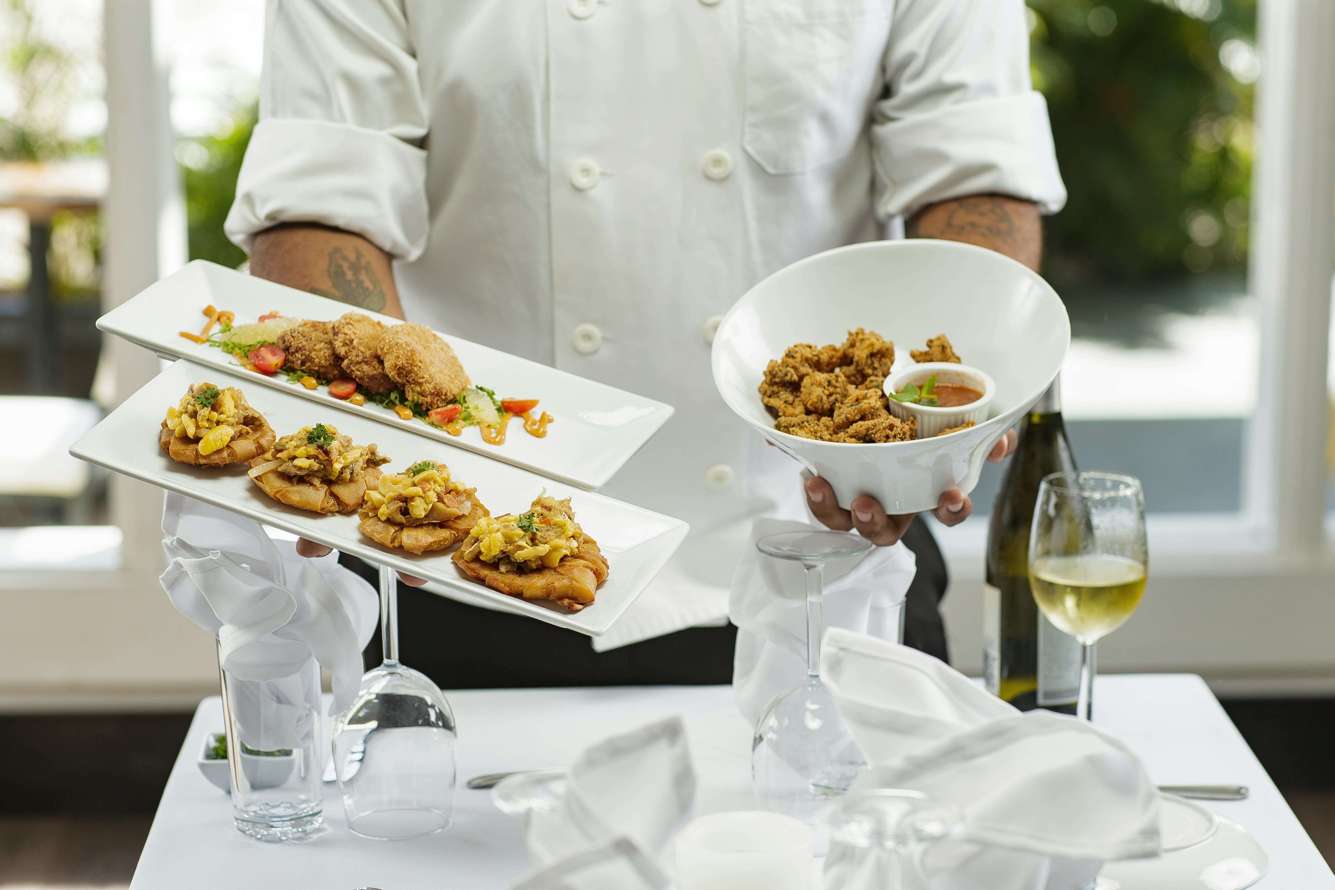 Image of a chef holding two different dishes with his hands, seems like fried chicken
